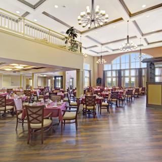A spacious dining hall with elegant chandeliers and neatly arranged tables and chairs.