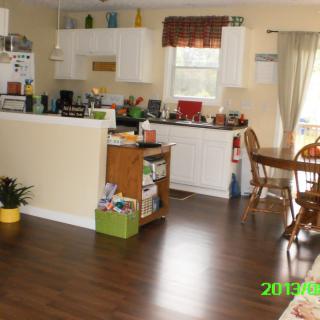 A cozy kitchen and dining area with wooden flooring and white cabinetry.