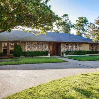 A suburban house with a large yard and driveway.