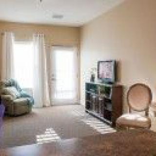 A cozy living room with a recliner, TV, and natural light from the window.