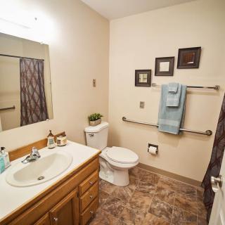 A tidy bathroom with a sink, toilet, mirror, and neatly arranged towels.