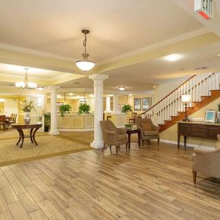 A spacious and elegantly designed lobby with wooden flooring, comfortable seating, and a staircase.