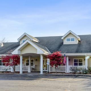 A charming residential building with a covered entrance and vibrant trees in front.