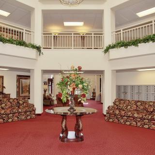 A spacious lobby with elegant furniture and floral centerpiece.