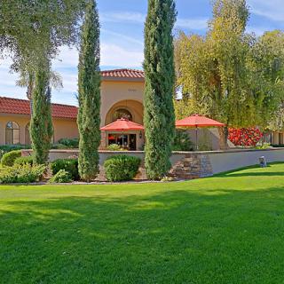 A scenic view of a building with red-tiled roof surrounded by lush green lawn and tall trees.