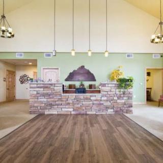 A welcoming reception area with a brick front desk, wooden flooring, and pendant lighting.