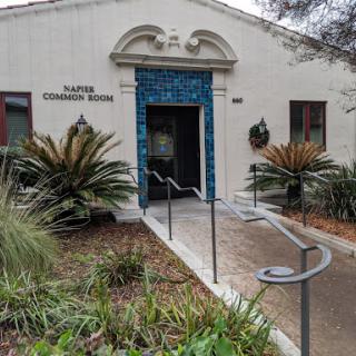 An inviting entrance to the community room, surrounded by lush greenery.
