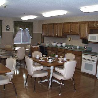 A cozy kitchen and dining area with wooden cabinets, a round table set for meals, and ample lighting.