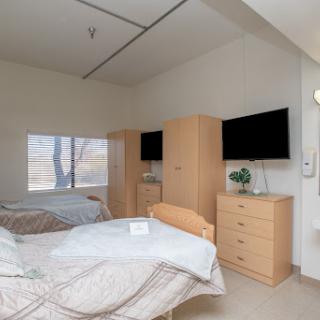 A well-furnished bedroom featuring two beds, modern cabinets, and televisions.