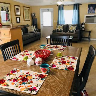 A cozy interior featuring a dining table with floral placemats and a connecting living room.
