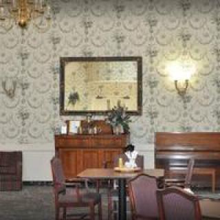 A vintage-style room featuring antique furniture, ornate wallpaper, and a chandelier.