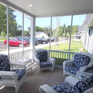 A cozy screened porch with wicker furniture overlooking a residential street.