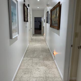 A well-lit hallway decorated with artwork and featuring tiled flooring.