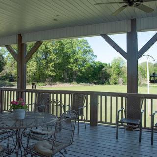 A shaded patio with a table and chairs overlooking a garden.