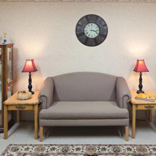A cozy living room setup with a sofa, side tables, and lamps under a wall clock.