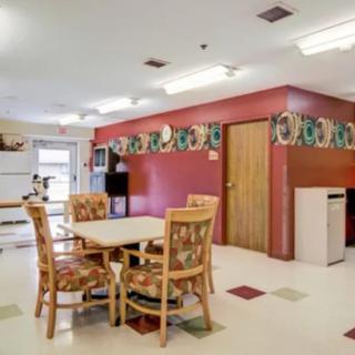 A kitchen and dining area featuring a table with chairs, a refrigerator, and decorative wall elements.