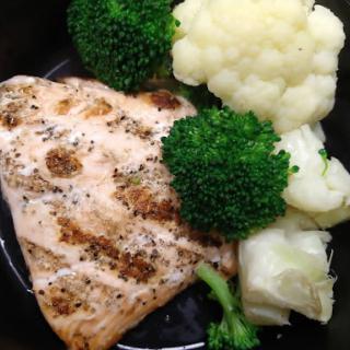 A nutritious meal featuring grilled salmon paired with steamed broccoli and cauliflower.