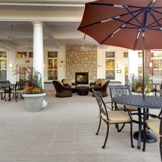 An inviting patio area with tables, chairs, and a central fireplace under a large umbrella.