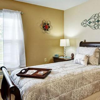 A cozy bedroom with a single bed, decorative wall art, and a nightstand with a lamp.