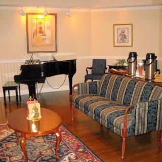 A cozy living room featuring a grand piano, striped sofa, coffee table, and a small refreshment area.