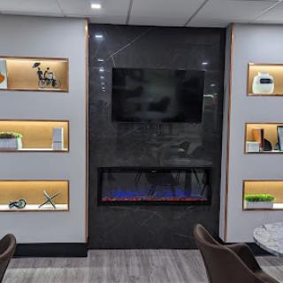 A stylish modern interior featuring illuminated shelves, a television, and an elegant fireplace.