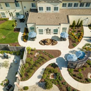 An aerial view of a landscaped residential backyard with winding paths, patios, and garden areas.