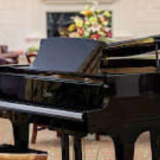 A grand piano positioned in an elegant indoor setting with floral decor in the background.