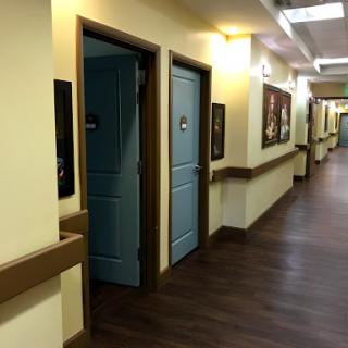 A view of a brightly lit hallway featuring blue doors and wall art.