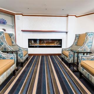 A modern living room with patterned chairs and a striped carpet, featuring a sleek fireplace.