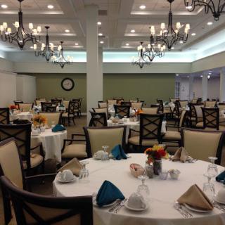 A beautifully arranged dining room featuring elegant tables and chandeliers, ready for an event.