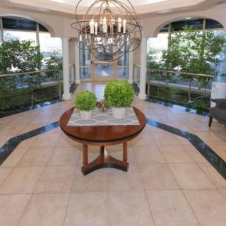 Luxurious foyer featuring a central round table with plants, a grand chandelier, and large windows.