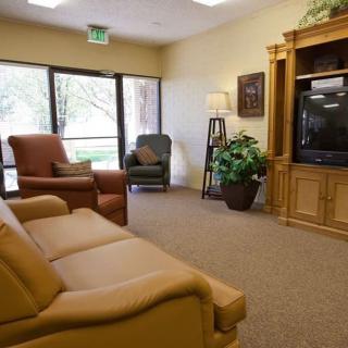 A cozy living room with comfortable seating, a TV, and indoor plants.