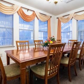 Elegant dining room with a large wooden table surrounded by chairs and adorned with decorative curtains.