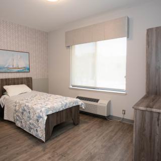 A modern, minimalist bedroom with a single bed and hardwood flooring.