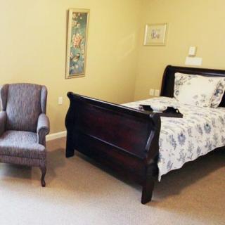 A cozy bedroom with a dark wooden bed and an upholstered armchair.