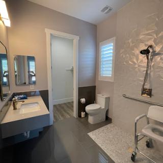 A modern bathroom featuring a sleek design, complete with a sink, toilet, and accessible shower setup.