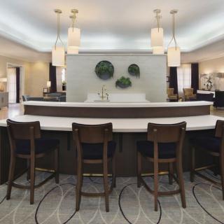 A modern kitchen interior with a sleek countertop and seating area, featuring pendant lights and decorative wall elements.