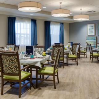 A well-decorated dining room with neatly arranged tables and chairs, illuminated by hanging lights.