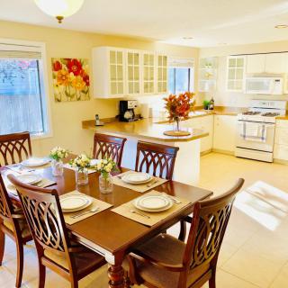 A bright, cozy dining room connected to the kitchen features a wooden table set for a meal.