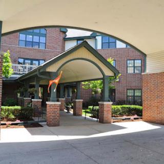 An inviting entrance with an archway leading to a brick building, surrounded by neatly trimmed bushes.
