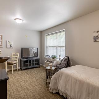 Cozy bedroom with a bed, TV, and comfortable seating by the window.