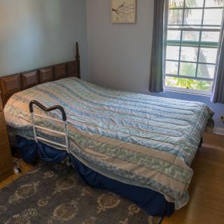 A bedroom with a bed featuring a side rail, next to a window.