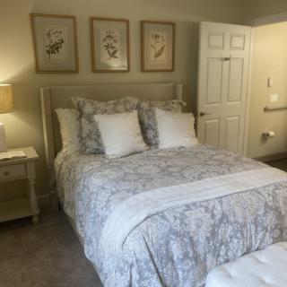A cozy and elegantly decorated bedroom with a bed, side table, and framed artwork on the wall.