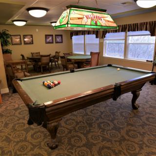 A cozy game room featuring a classic pool table and comfortable seating.