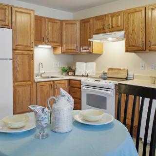 A cozy kitchen with wooden cabinets and a dining table set for two.