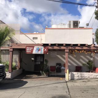 Exterior view of a small restaurant with a parking area and cloudy sky.