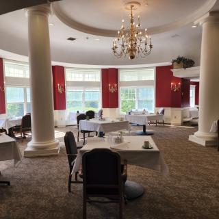An elegant restaurant dining room with large windows, red walls, and a chandelier.