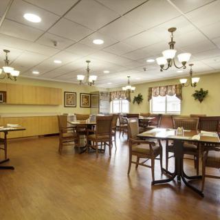 A spacious dining room with wooden tables and chairs, adorned with elegant lighting fixtures.