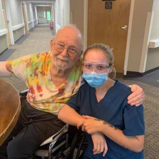 A heartwarming moment between a caregiver and an elderly resident, sharing smiles in a healthcare setting.