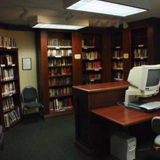 A small library room with bookshelves and a desk with a computer.